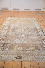 Distressed Oushak rug texture with faded geometric motifs in beige, ivory, and silver.