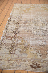 Distressed Oushak rug edge showcasing muted beige, ivory, and bronze patterns.