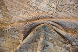 Distressed Oushak rug pile revealing faded beige, ivory, and bronze patterns.