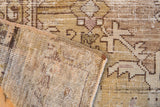 Distressed vintage Oushak rug fold showcasing worn pile, muted patterns, and visible woven foundation.