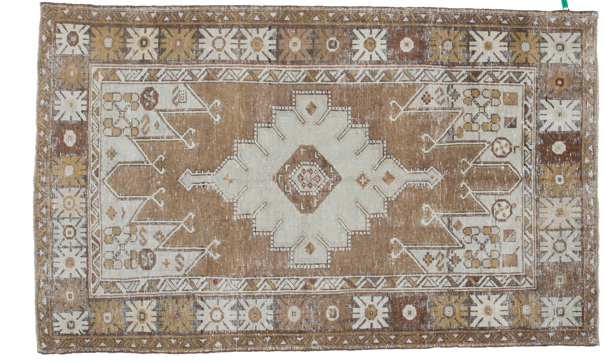 Distressed Turkish Oushak rug with a geometric medallion in pale silver, bronze, and earth tones.