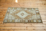 Decorative geometric medallion on distressed vintage Oushak rug with earthy bronze tones.