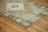 Distressed geometric border and corner of the Oushak rug in pale silver and bronze tones.