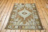 Distressed Oushak rug corner, geometric patterns in bronze, pale silver, and frayed fringe.