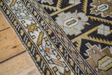 Angled detail of antique rug's geometric border and charcoal field with earth tones.