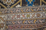 Geometric palmettes, serrated leaf motifs, and earth tones on an antique Caucasian rug.