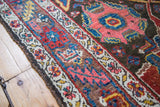 Antique Bidjar rug's edge displaying classic geometric border and field patterns in deep rose, blue, and brown.