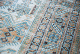 Worn geometric patterns in faded blue, tan, and ivory on a distressed Afshar rug.