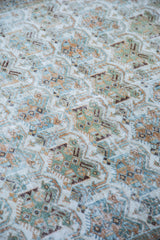 Distressed texture and allover repeating pattern of a vintage Afshar rug in ivory, soft teal, and earthy tones.
