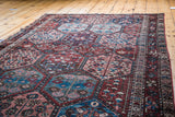 Distressed Baktiary rug showing hexagonal panels with pinwheel and tree motifs.