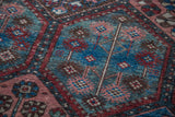 Distressed antique Baktiary rug detail: blue, red rust, and soft pink pinwheel and tree motifs.