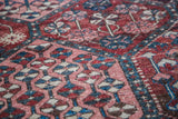 Distressed Antique Baktiary rug panel: pinwheel, tree motifs in muted red, soft blue.