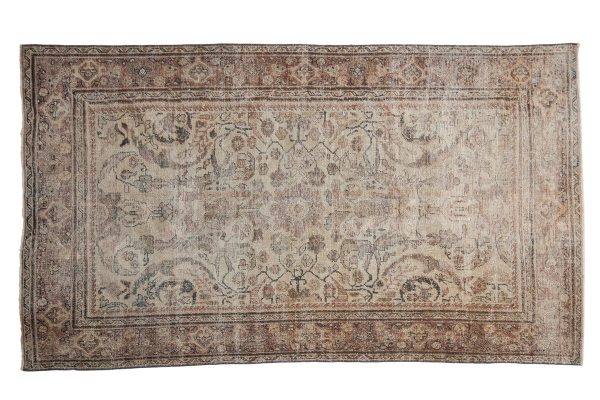 Distressed vintage Mahal carpet, large scale floral pattern in faded beige, brown, charcoal tones.