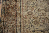 Worn texture and muted brown, beige motifs of a distressed Mahal carpet.