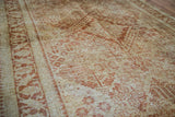 Worn orange-rust patterns on golden ivory vintage Joshegan rug texture.