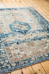 Geometric motifs across the ivory field of the Karaja rug, featuring aqua and navy blue abrashes.