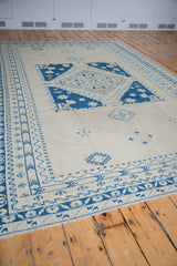 Detailed blue geometric border patterns and distressed field on a vintage Oushak carpet.