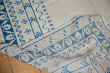 Geometric border pattern of the distressed Oushak rug in blue and cream tones.
