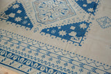 Vintage Oushak carpet's distressed blue geometric borders and intricate patterns on light field.