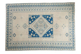 Vintage distressed Oushak rug featuring a geometric blue, tan, and beige medallion with intricate borders, 6'9