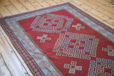 Deep red field with geometric triple shadow medallion motif and soft light blue border.