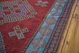 Caucasian style hand-knotted rug with deep red geometric field and soft light blue border.