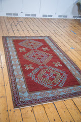 Geometric motifs on the soft light blue border of the deep red Caucasian rug.