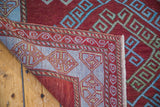 Corner view of a New Caucasian rug, revealing hand-knotted back and geometric border.