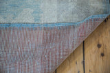 Lifted corner of vintage Oushak rug reveals hand-knotted foundation and aqua seafoam pile.
