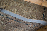 Geometric motifs and rich bronze browns on the folded Vintage Turkmen rug's pile and foundation.