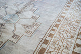 Distressed Oushak runner detail: soft light mauve ivory pile, blue medallion, and bronze border.