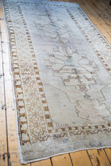 Distressed Oushak runner, soft overdye aesthetic on light mauve field with geometric medallions.
