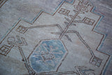 Distressed Oushak rug detail: light blue geometric pattern on a soft mauve field.
