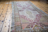 Distressed Oushak runner's textured pile, showcasing geometric plum, ivory, and coral patterns.