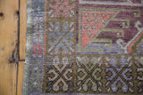 Distressed Oushak rug runner with geometric pattern in plum, bronze, mauve, and coral tones.