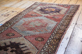 Distressed Oushak rug runner close-up, showing geometric patterns in brick red, silvery platinum, and orange.