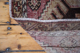 Vintage Oushak rug corner detail showing worn geometric pile, fringe, and hand-knotted back.