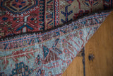 Antique Karaja rug corner folded, revealing geometric pile, beige border, and hand-knotted foundation.