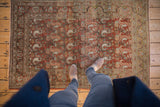 Distressed vintage Birjand rug with red rust background, faded paisley boteh motifs, and worn texture.