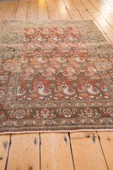 Distressed vintage Birjand rug's red rust paisley boteh pattern and border.