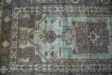 Vintage Oushak rug's stylized geometric motif in soft seafoam green and bronze.
