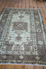 Vintage Oushak rug's off-white fringe and detailed geometric pattern in soft seafoam and bronze.