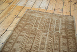 Geometric design and texture of a vintage Belouch rug in neutral ivory and golden bronze.