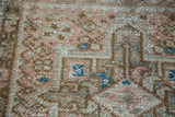 Close-up of vintage Karaja rug, showing low pile, ivory, coral, bronze, and blue geometric motifs.