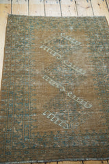 Faded copper and teal charcoal blue motifs on a distressed vintage Afghan rug corner.