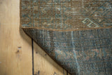 Distressed Afghan rug, displaying its faded copper, teal, ivory pattern and hand-knotted construction.