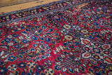 Detail of the vintage Sarouk rug's jewel red field with intricate blossoming floral motifs.