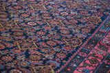 Traditional Persian Bidjar rug's deep navy Herati pattern, vivid coral rose border, and green accents.