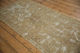 Vintage Oushak runner with distressed texture, bronze, ivory tones, and scrolling wave border.