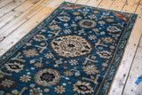 Antique Caucasian rug: light blue, teal, and tan arabesques on deep indigo field.